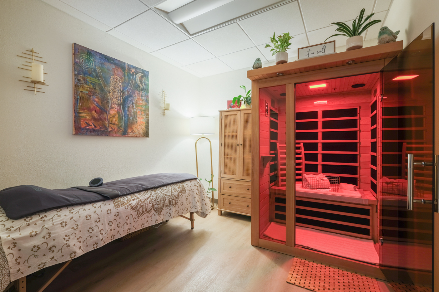 Infrared sauna glowing red beside a treatment table in the sauna room at Flora Integrated Wellness, Escondido, CA